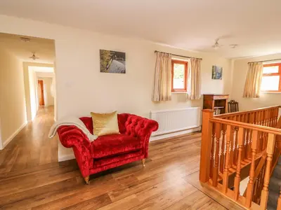 a living room with a red chair and wooden floors at Treboeth in Knighton