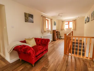 a living room with a red chair and wooden floors at Treboeth in Knighton