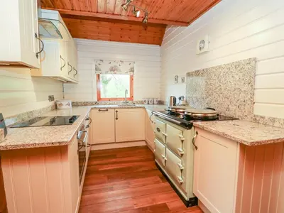 a kitchen with white walls and wooden floors and a stove at Pines Pitch in Knighton