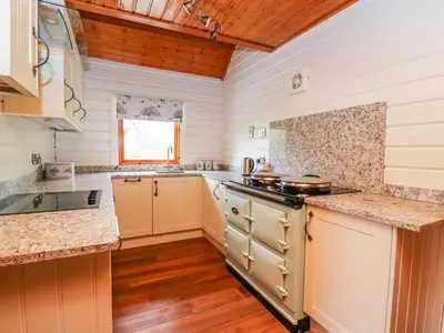 a kitchen with white walls and wooden floors at Pines Pitch in Knighton