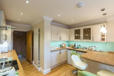 a kitchen with white cabinets and a wooden counter top at Woodland View Holiday Apartment in Llanwrda