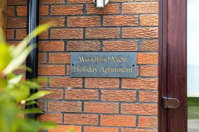 a sign on the side of a brick wall at Woodland View Holiday Apartment in Llanwrda