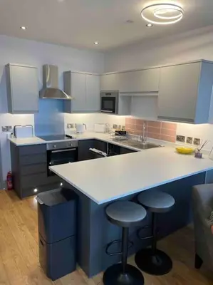 a large kitchen with a counter and stools in it at Luxury Sea View Apartment - One Bedroom in Aberystwyth