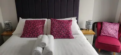 a bedroom with a bed with pink pillows at Luxury Sea View Apartment - One Bedroom in Aberystwyth