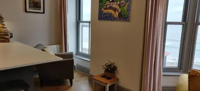 a living room with windows and a table and a chair at Luxury Sea View Apartment - One Bedroom in Aberystwyth