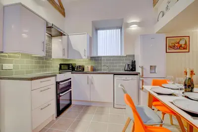 a kitchen with white cabinets and a table with orange chairs at 3 Bed in Machynlleth oc-bow91 in Penegoes
