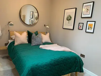 a bedroom with a green bed with a mirror at The Folly in Ludlow