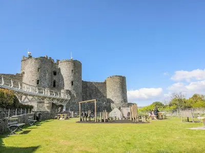 a castle with people sitting in front of it at Harlech Apartments - Matholwch in Harlech
