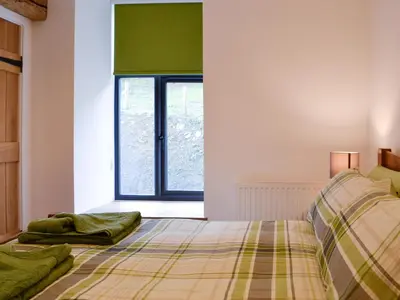 a bedroom with a bed and a window at Pistyll Gwyn in Llanwrthwl