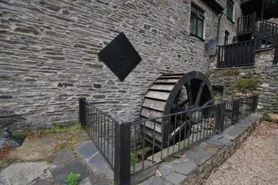 a stone wall with a black fence next to a building at The Coach House Annexe in Llangollen