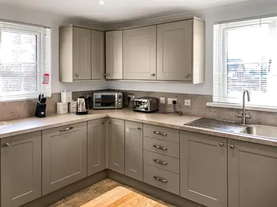 a kitchen with white cabinets and a sink at Brynich Villa in Brecon