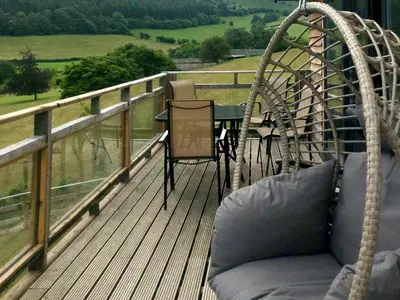 a porch with a swing and a table on a deck at Offa's Dyke Lodge - Uk10835 in Old Radnor