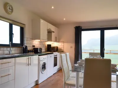 a kitchen with white cabinets and a table with chairs at Offa's Dyke Lodge - Uk10835 in Old Radnor