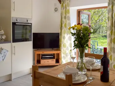 a kitchen with a table with a vase of flowers at Parlwr - Uk11210 in Cwrt-newydd
