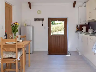 a kitchen with a wooden table and a door at Parlwr - Uk11210 in Cwrt-newydd