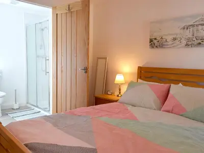 a bedroom with a bed and a bathroom with a window at Parlwr - Uk11210 in Cwrt-newydd