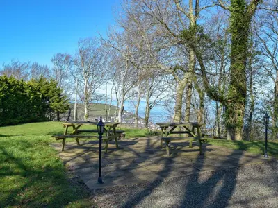 a group of picnic tables in a park at Cynefin Cottage in New Quay