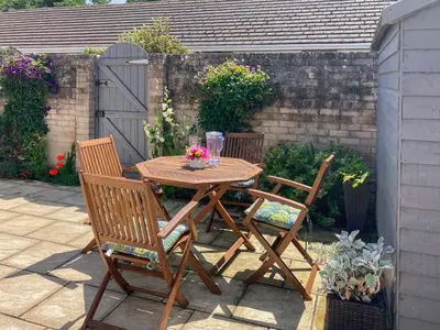 a wooden table and chairs with flowers on a patio at Gwynt Y Môr in Tywyn