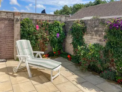 a white chair sitting on a patio next to a brick wall at Gwynt Y Môr in Tywyn