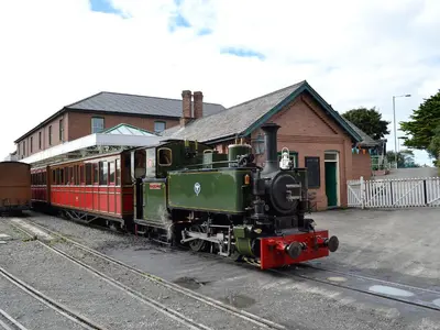 a green and red train parked at a train station at Gwynt Y Môr in Tywyn