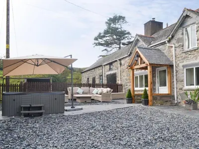 a patio with a couch and an umbrella in front of a house at Tyddyn Eli in Llangwm