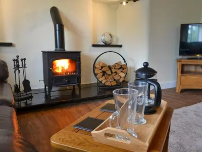 a living room with a coffee table with a wood stove at Tyddyn Eli in Llangwm