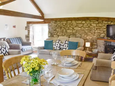 a living room with a table and a stone wall at Woodland View-Uk11826 in Llandefaelogfâch