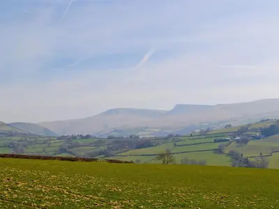 a green field with hills in the background at Maes Y Bryn Farmhouse in Llanwrda