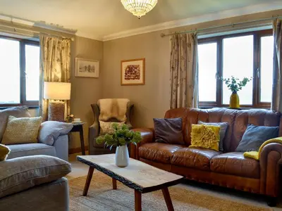 a living room with a brown leather couch and chairs at Maes Y Bryn Farmhouse in Llanwrda