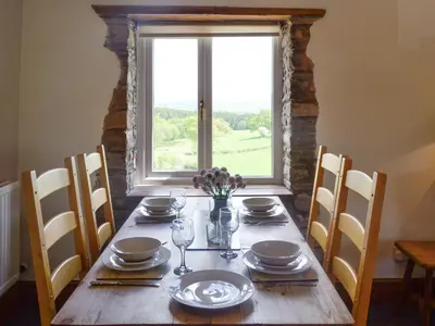 a wooden table with chairs and a large window at Mountain View-Uk11825 in Llandefaelogfâch