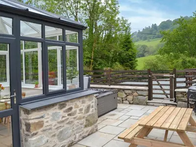 a patio with a grill and a wooden table at Ysgoldy Salem in Mallwyd