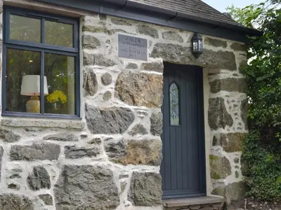 a stone house with a black door and a window at Ysgoldy Salem in Mallwyd