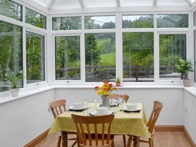 a dining room with a table and chairs and windows at Ysgoldy Salem in Mallwyd