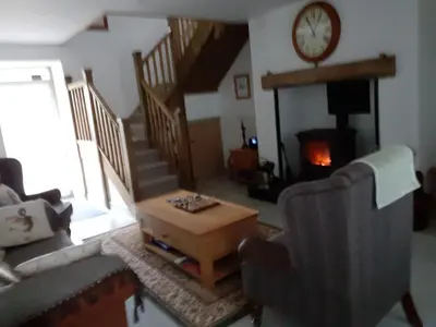 a living room with a table and a clock on the wall at Rhydyfran House Aberaeron, Lampeter, West Wales, Ceredigion in Lampeter
