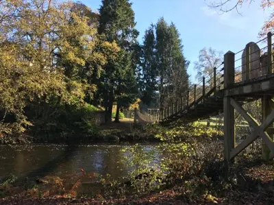 a bridge over a river with trees and water at 49 Irfon Lodge in Builth Wells