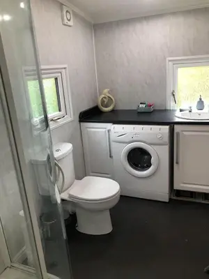 a bathroom with a toilet and a washing machine at 49 Irfon Lodge in Builth Wells