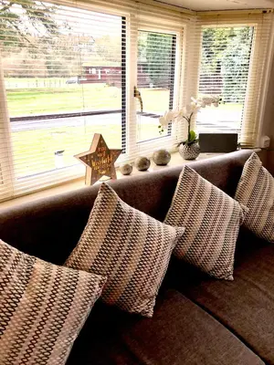 a couch with pillows sitting in front of a window at 49 Irfon Lodge in Builth Wells