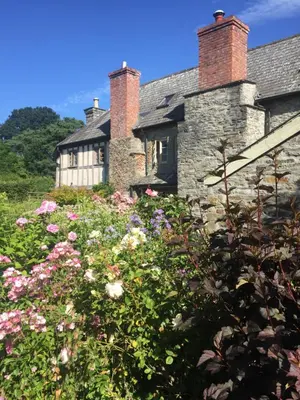 an old stone house with flowers in front of it at Lower House Farm B&B, Herefordshire in Hergest