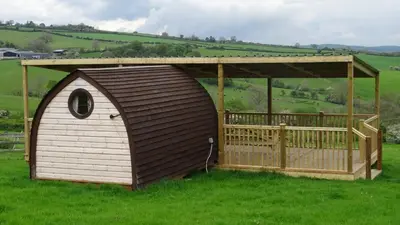 a dog house with a roof on a field at Woodbatch Camping & Glamping in Bishops Castle