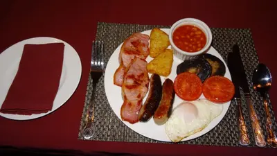 a plate of breakfast food with bacon eggs potatoes and beans at Woodbatch Camping & Glamping in Bishops Castle
