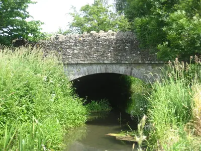 a stone bridge over a river with a tunnel at Walford Court in Leintwardine