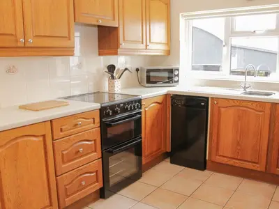 a kitchen with wooden cabinets and a black stove top oven at Caesamson in Caersws