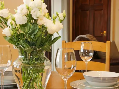 a vase of white flowers sitting on a table with glasses at Caesamson in Caersws