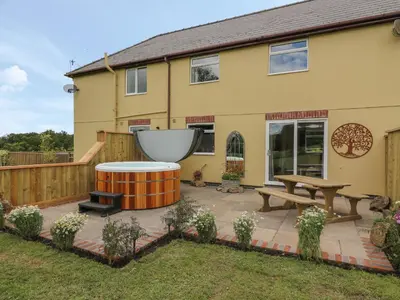 a patio with a table and a bench in front of a house at Owl Cottage in Llandrindod Wells