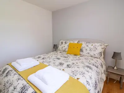a bedroom with a bed with a yellow pillow and towels at Owl Cottage in Llandrindod Wells