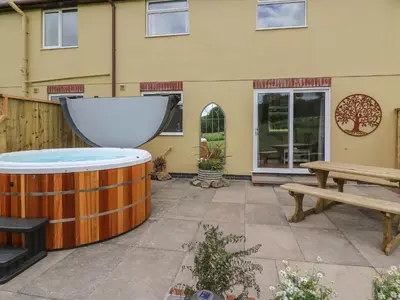 a patio with a hot tub and a bench at Owl Cottage in Llandrindod Wells