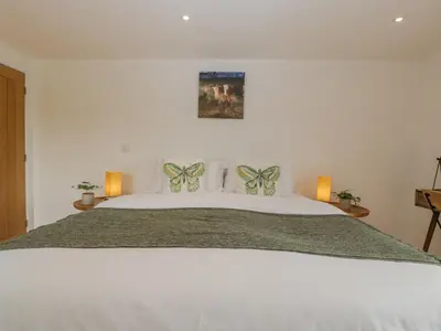 a bedroom with a large white bed with two butterfly pillows at The Dutch Barn in Leominster