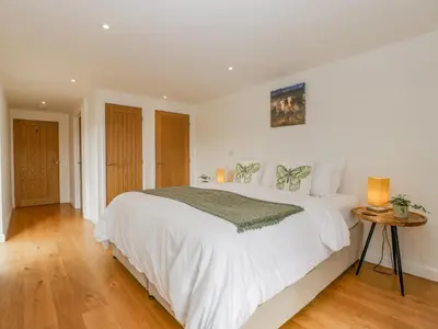 a bedroom with a large white bed and a wooden floor at The Dutch Barn in Leominster