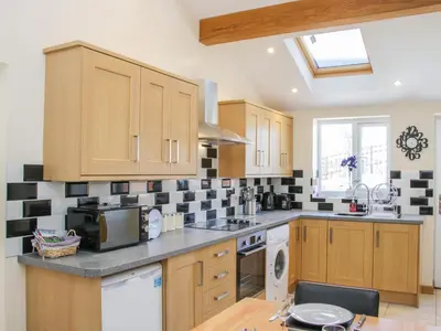 a kitchen with wooden cabinets and black and white tiles on the wall at The Boundary Annex in Bishops Castle