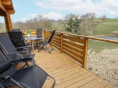 a wooden deck with chairs and a table on it at Manor Farm Lodges - Red Kite Lodge in Newtown